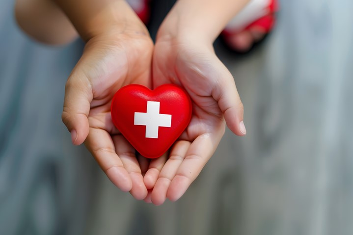 Hands holding a heart with a medical cross
